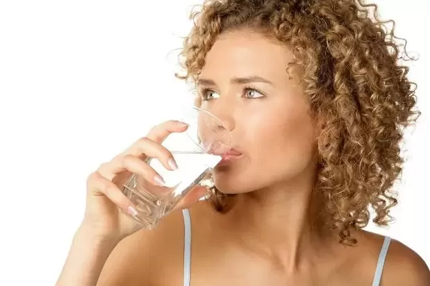 La niña sigue una dieta para perezosos, bebiendo un vaso de agua antes de comer